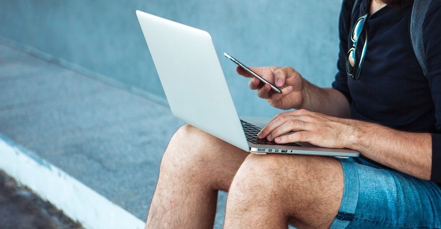 Kirjanpidon säilytysaika. Miesyrittäjä selaa kannettavaa tietokonetta ja älypuhelinta