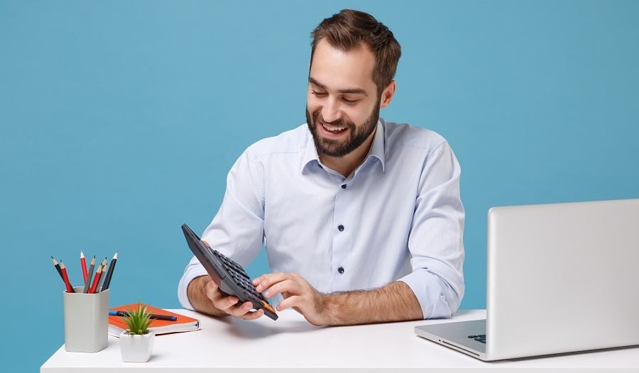 Kirjanpidon säilytysaika. Miesyrittäjä käyttää laskinta työpöydän ääressä