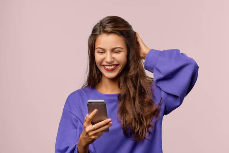 nainen tarkistaa laskua puhelimella