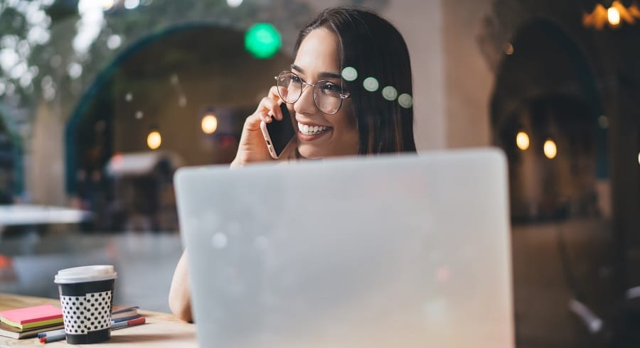 Töitä opiskelijalle. Iloinen nuori nainen työskentelee ja puhuu puhelimeen