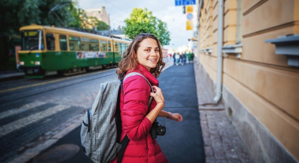 Töitä opiskelijalle. Nuori nainen kävelee kaupungilla reppu selässä