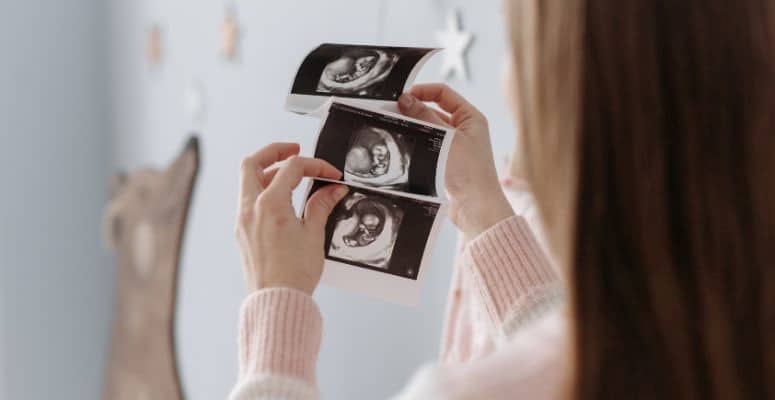 Kädet pitelevät ultraäänikuvia vauvasta. Kuvituskuva. Yrittäjän sosiaaliturva.